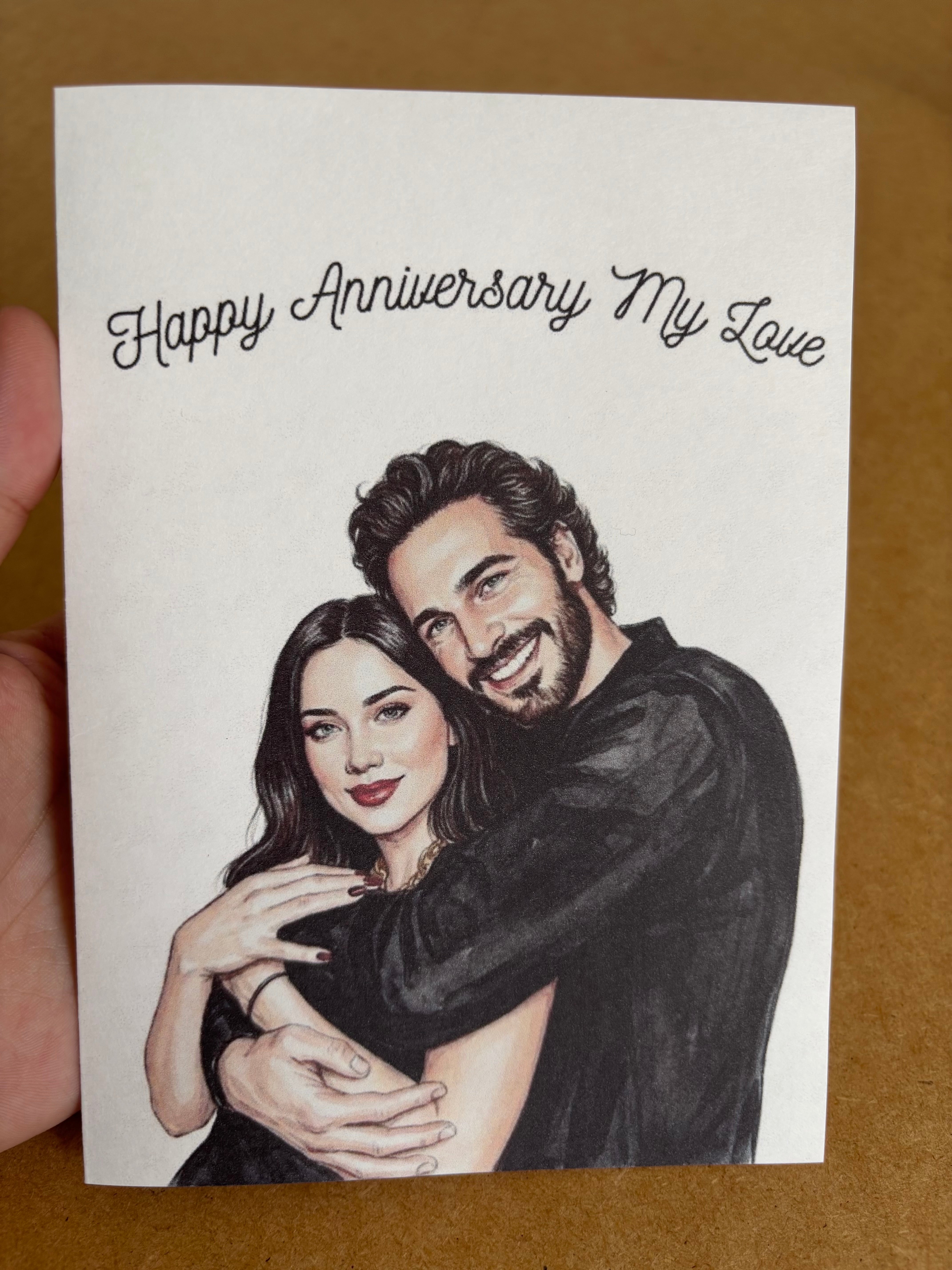 Hand holding a custom watercolor anniversary greeting card created from a personal photo.